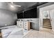Living room featuring tile floors, 2 wall mounted TVs, and nearby staircase at 6018 Owens St, Arvada, CO 80004