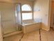 Bright bathroom featuring a tub under an arched window and a glass enclosed shower at 21561 E 48Th Pl, Denver, CO 80249