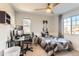 Bright bedroom setup with dual windows, ceiling fan, neutral colors, and a dedicated desk with computer equipment at 11013 Valleybrook Cir, Highlands Ranch, CO 80130