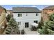 A beautiful, light grey two-story home with a wooden deck, an umbrella-covered table and mature evergreens in the backyard at 3129 Open Sky Way, Castle Rock, CO 80109