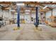 Spacious garage interior featuring a car lift and ample workspace with overhead lighting and exposed beams at 5285 E State Highway 86, Franktown, CO 80116