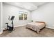Bedroom featuring neutral walls, carpet, and a large window offering ample natural light and an exercise bike at 6532 S Tempe St, Aurora, CO 80016