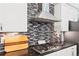 The kitchen backsplash is a horizontal mosaic with stainless appliances, dark countertops, and white cabinets at 6532 S Tempe St, Aurora, CO 80016