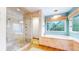 A beautifully renovated bathroom with travertine tile and a glass enclosed shower and separate tub area at 540 Columbine Ave, Broomfield, CO 80020
