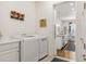 Well-lit laundry room with a washer, dryer, sink, and decor overlooking the dining room at 25049 E Alder Dr, Aurora, CO 80016
