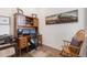 Cozy home office with wooden desk, dual monitors, rolling chair, wooden rocker, and decorative train art at 25049 E Alder Dr, Aurora, CO 80016
