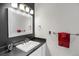 Well-lit bathroom featuring a modern mirror and sleek black countertop with a white sink and red towels at 3419 Traver Dr, Broomfield, CO 80023