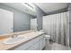 This bathroom has a double sink vanity, soft grey walls, and a shower tub with curtain at 5229 Nighthawk Pkwy, Brighton, CO 80601