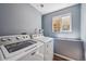 Laundry room with a window and modern washer and dryer units at 5229 Nighthawk Pkwy, Brighton, CO 80601