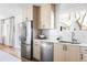 Bright kitchen featuring stainless steel refrigerator and dishwasher with light wood cabinets and window view at 965 S Jersey St, Denver, CO 80224