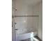 Bathroom with a white tiled tub and shower and a decorative accent at 311 Elm St, Lochbuie, CO 80603