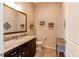 Well-lit half bath with a granite countertop, dark cabinets, and decorative wall planters at 3367 New Haven Cir, Castle Rock, CO 80109