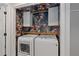 Stylish laundry room with modern washer and dryer, floral wallpaper, and white storage cabinets at 7975 S Gaylord Way, Centennial, CO 80122