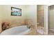 Elegant bathroom featuring a soaking tub, stone tile surround, and glass-enclosed shower at 4932 Democrat Dr, Broomfield, CO 80023