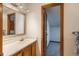 This bathroom has a wooden vanity with a white countertop, a mirror, and an open door showing storage at 1585 W Briarwood Ave, Littleton, CO 80120