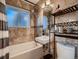 Beautiful bathroom with neutral tile, bathtub, and a sink with a modern shelf perfect for an urban home at 40 Benton St, Lakewood, CO 80226