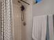 Shower with white tile, shower head, chrome hardware and black and white striped shower curtain at 40 Benton St, Lakewood, CO 80226