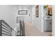 Bright hallway features modern railing, neutral carpet, and connects to a laundry area with gray cabinetry at 128 Chapel Hill Cir, Brighton, CO 80601