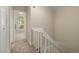 A carpeted hallway featuring a white banister and view into a room with a large arched window at 18171 E Arizona Ave # B, Aurora, CO 80017