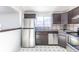 Kitchen with stainless steel appliances, dark brown cabinets, and neutral tile backsplash at 3570 Center Ave, Denver, CO 80219