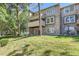 Multi-level townhome with a brick facade and private balcony nestled among mature trees and green lawns at 6731 S Kearney Ct, Centennial, CO 80112
