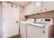 Functional laundry area with modern appliances and overhead cabinets, offering convenience and storage at 6731 S Kearney Ct, Centennial, CO 80112