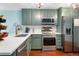 Well-lit kitchen with modern stainless steel appliances, light countertops, and sage-colored cabinetry at 15104 E Utah Pl, Aurora, CO 80012