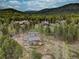 Stunning aerial view of a mountain home surrounded by lush forest and mature trees with a wooden fence surrounding the property at 9288 Krashin Dr, Conifer, CO 80433