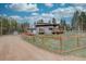 Charming grey home featuring a fenced yard, wooden deck, and lovely surroundings on a sunny day at 9288 Krashin Dr, Conifer, CO 80433