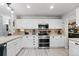 Well-lit kitchen with white cabinets, stainless steel appliances and woodgrain-style flooring at 2805 Masters Ln, Castle Rock, CO 80104