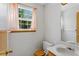 Bright bathroom featuring a window, a toilet, and a sink with wood accents at 12043 E Ford Cir, Aurora, CO 80012