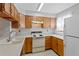 Functional kitchen featuring wood cabinets, an oven, and a white refrigerator at 12043 E Ford Cir, Aurora, CO 80012