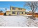 Backyard with a spacious lawn, deck, and mature trees provides a serene outdoor setting, especially in winter at 8694 E Eastman Ave, Denver, CO 80231