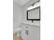 Stylish half bathroom featuring a vanity with black hardware, modern mirror, and hardwood floors at 8694 E Eastman Ave, Denver, CO 80231