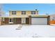 Charming two-story home with brick accents, a covered porch, and an attached two-car garage in a snow-covered setting at 8694 E Eastman Ave, Denver, CO 80231