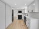Open concept kitchen features white cabinets, modern appliances, and light wood floors at 8694 E Eastman Ave, Denver, CO 80231