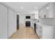 Well-lit kitchen with stainless steel appliances, white cabinets, quartz countertops and wood flooring at 8694 E Eastman Ave, Denver, CO 80231