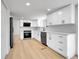 Modern kitchen with white cabinets, stainless steel appliances, and hardwood floors at 8694 E Eastman Ave, Denver, CO 80231
