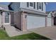 Close-up of the front of a two-story home featuring an attached two-car garage with brick accents and a well-kept lawn at 2195 S Espana St, Aurora, CO 80013