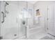 Clean bathroom featuring a glass enclosed shower with bench, soaking tub, and white marble tile at 1481 Red Poppy Way, Brighton, CO 80601