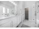 Elegant bathroom featuring double sinks, a large mirror, marble floors, and a glass-enclosed shower at 1481 Red Poppy Way, Brighton, CO 80601