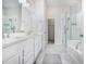 Bright bathroom featuring double sinks, a walk-in closet, a glass shower, and a bathtub at 1481 Red Poppy Way, Brighton, CO 80601