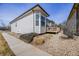 Exterior view of the home showcasing the neutral toned siding, stone landscaping, and an outdoor deck at 1481 Red Poppy Way, Brighton, CO 80601