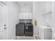Laundry room featuring dark front load washer and dryer, a utility sink, and bright white storage cabinets at 1481 Red Poppy Way, Brighton, CO 80601