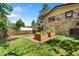 Backyard view featuring raised garden beds and a lawn with an attractive brick home at 12408 E Ohio Ave, Aurora, CO 80012