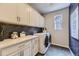 Functional laundry room with white cabinets, countertop space, a washer and dryer, and stylish backsplash at 13812 Honey Hush Trl, Parker, CO 80134