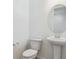 Powder room featuring a pedestal sink, modern faucet, round mirror and a toilet at 8295 Snake River St, Littleton, CO 80125