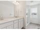 Bright bathroom featuring double sinks, white cabinetry, and a glass-enclosed shower at 8295 Snake River St, Littleton, CO 80125