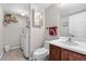Cozy bathroom combined with laundry featuring tiled floors, a vanity, and modern appliances at 21851 Omaha Ave, Parker, CO 80138