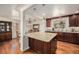 Kitchen with hardwood floors and large island with granite countertops, sink, and dark cabinets at 6305 Yukon St, Arvada, CO 80004